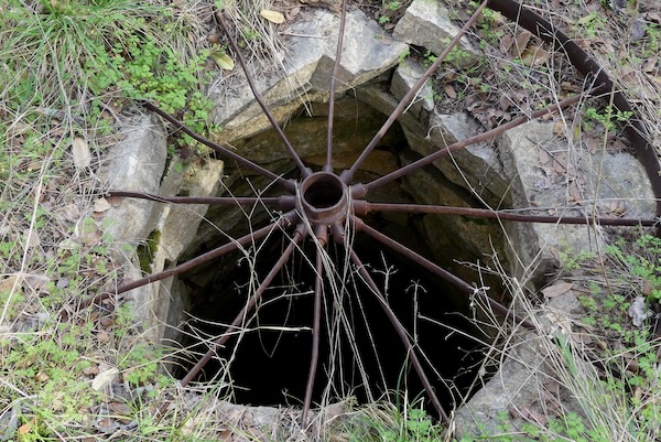 An old well covered by an old wagon wheel. Photo by Michael Smith.