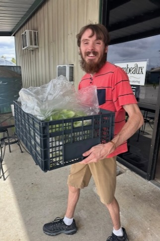 GrowOn volunteer carries a box of fresh produce.
