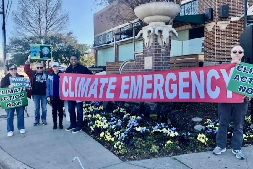Protesters holding "Climate Emergency" banner outside a building.