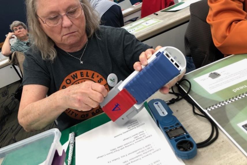 Woman using a handheld scanner in a classroom setting.