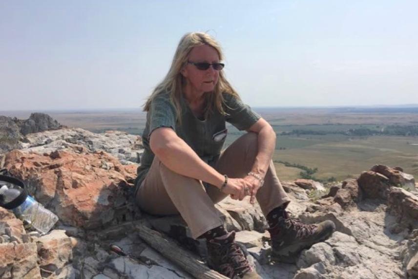 Woman sitting on rocky hill, looking out over landscape.