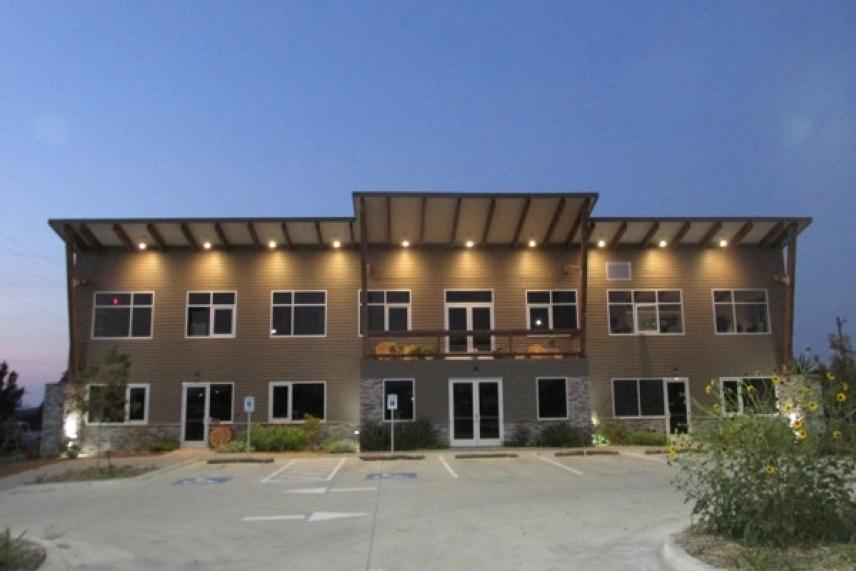 Two-story building with lights on, at dusk.