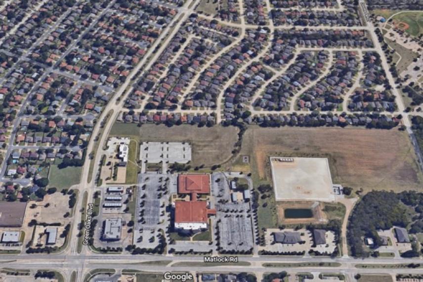 Aerial view of suburban neighborhood with roads and open fields.