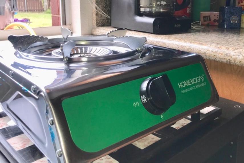 Single-burner portable gas stove on a kitchen countertop.
