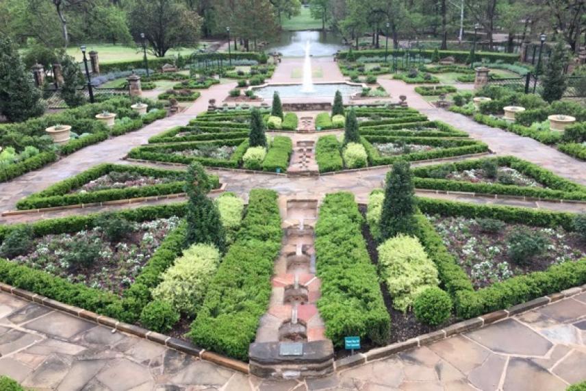 Symmetrical garden with fountain, pathways, and neatly trimmed hedges.