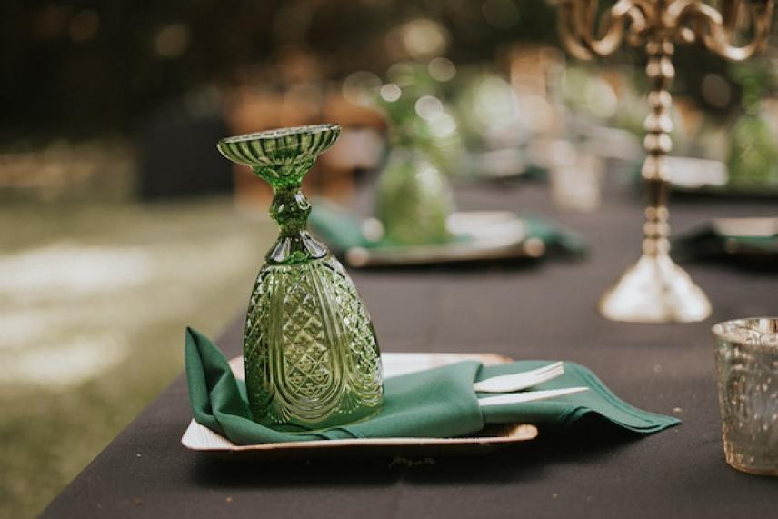 Green glass upside down on napkin at elegantly set outdoor table.