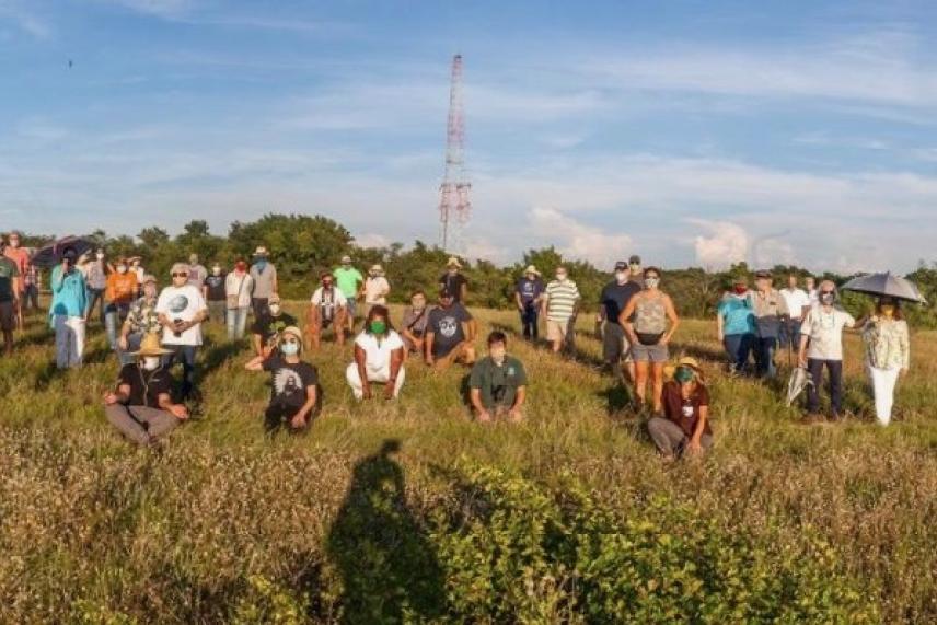 Group of people standing in a grassy field with a tower in the background.