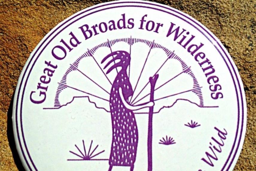 Round logo with purple figure holding a staff, surrounded by text.