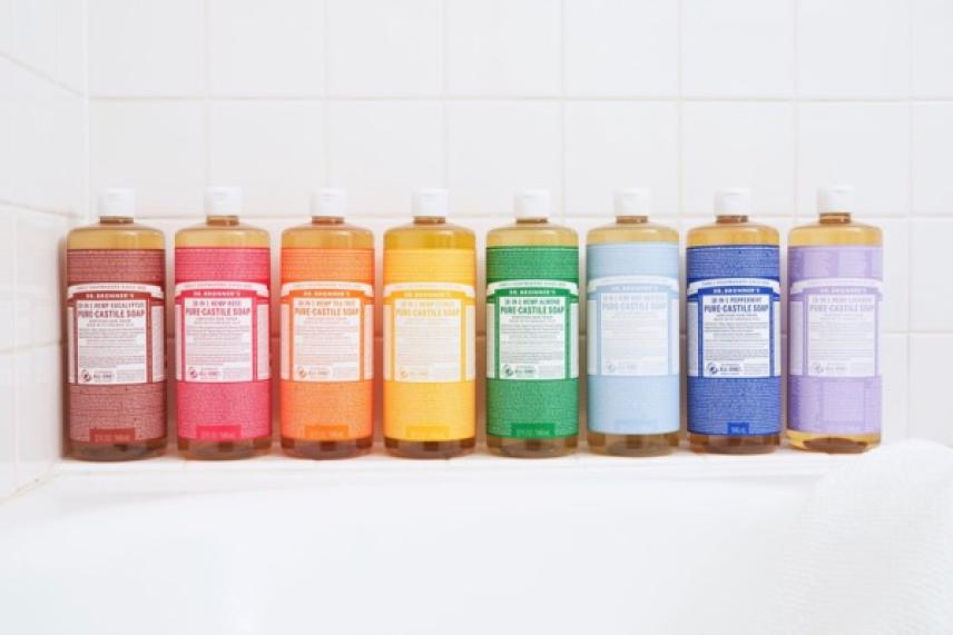 Colorful soap bottles arranged in a row on a bathtub edge.