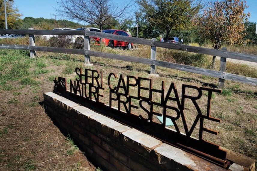 Sheri Capehart Nature Preserve sign by a wooden fence and trees.