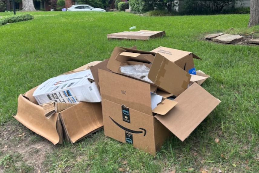 Cardboard boxes discarded on green grass in a suburban yard.