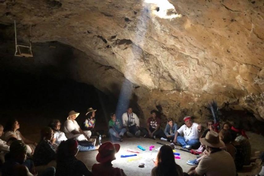 Group of people sitting in a circle inside a dimly lit cave.