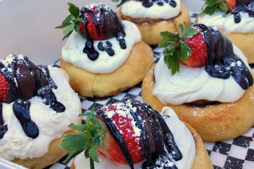Pastries topped with cream, strawberries, and chocolate drizzle.