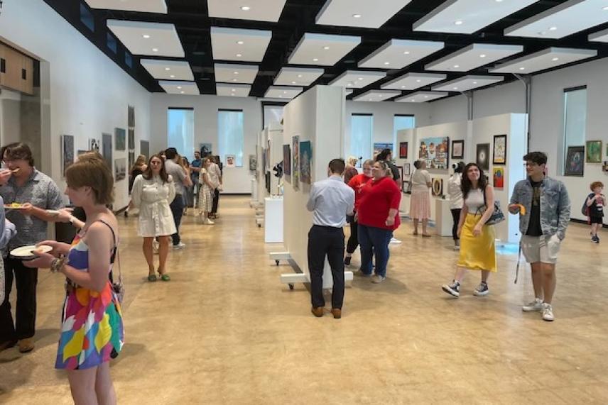 People viewing art in a spacious gallery with high ceilings.