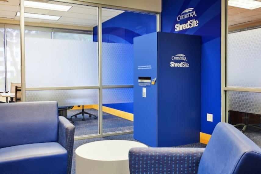 Lobby with blue armchairs, a round white table, and a blue office kiosk.