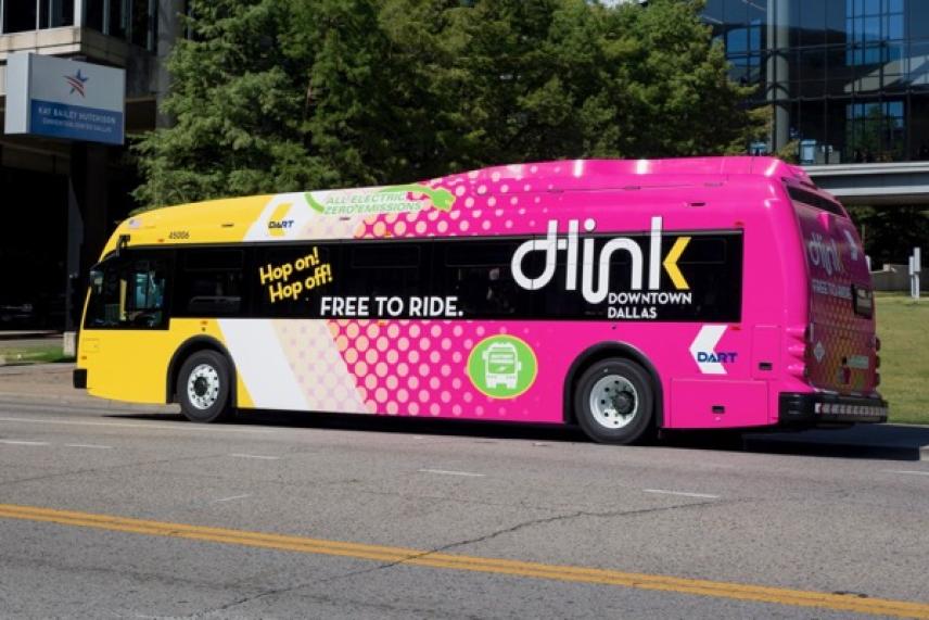 Colorful city bus with "Dlink" branding, parked beside a grassy area.