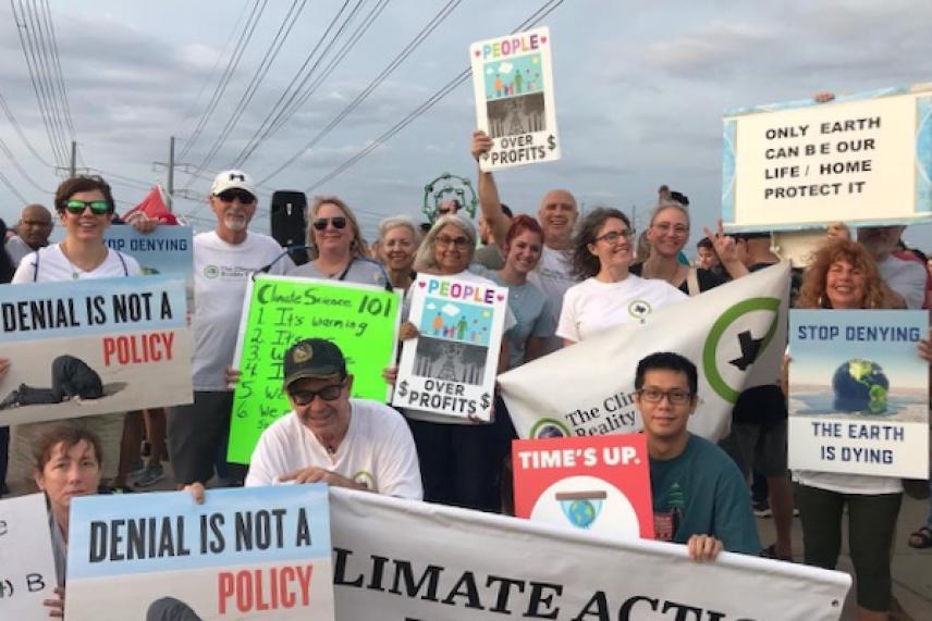 Group of people at climate protest holding signs, some with environmental messages.