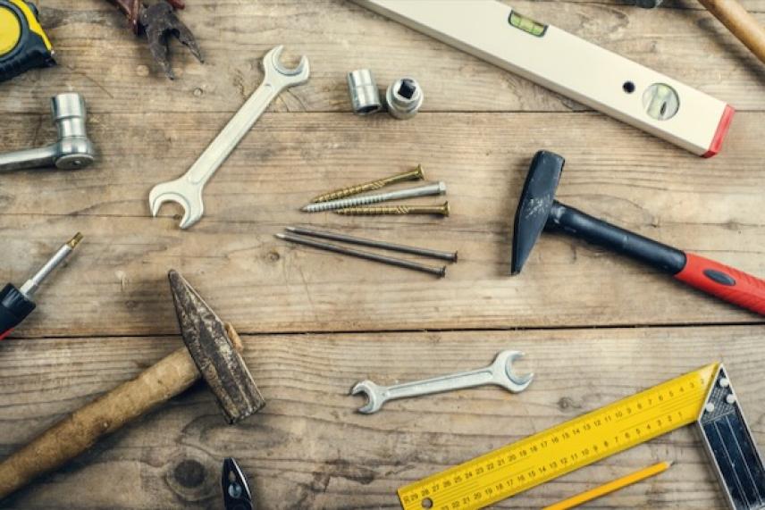 Various tools on a wooden surface including wrenches, hammers, and screws.
