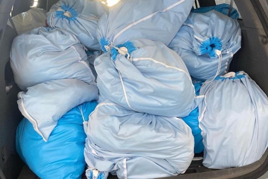 Blue bags piled in a car trunk.