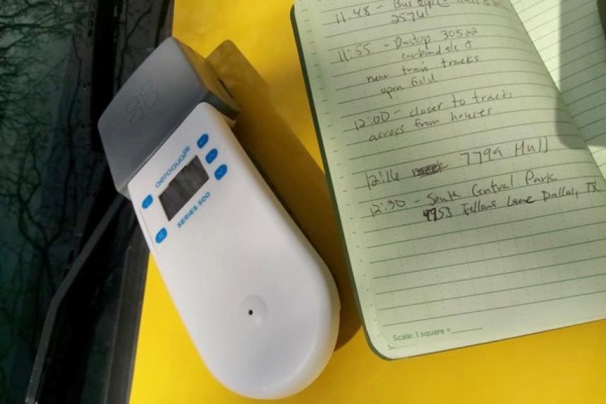 Portable device on yellow surface near open notebook.