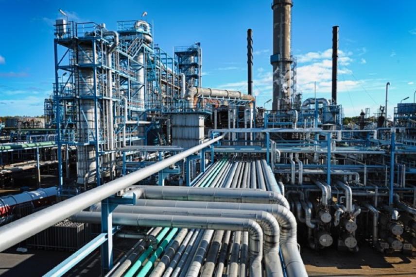 Industrial refinery with pipes and chimneys under a clear blue sky.