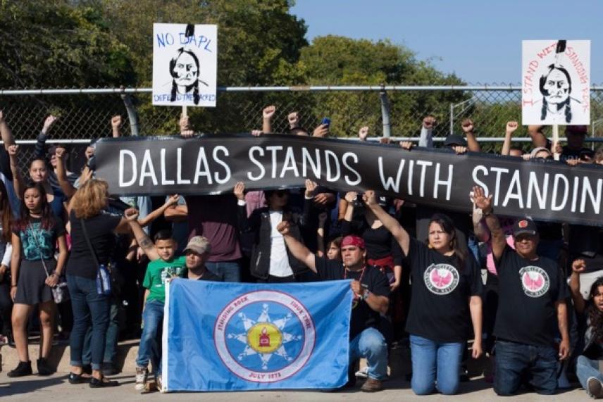 Protesters holding banners and a flag, raising fists in solidarity.