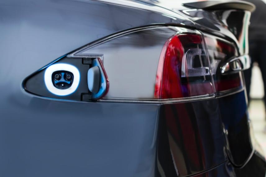 Electric car charging port on a sleek, gray vehicle.