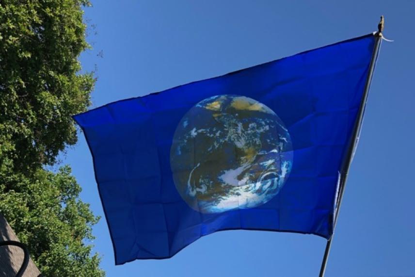 Blue flag with Earth image, blue sky background.