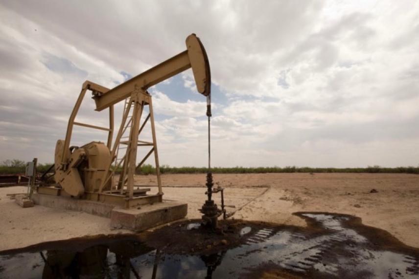 Oil pumpjack in a barren landscape under cloudy skies.