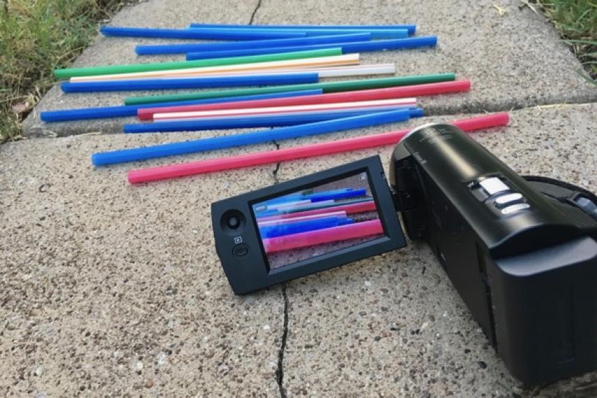 Colorful rods scattered on concrete with a camera capturing them.