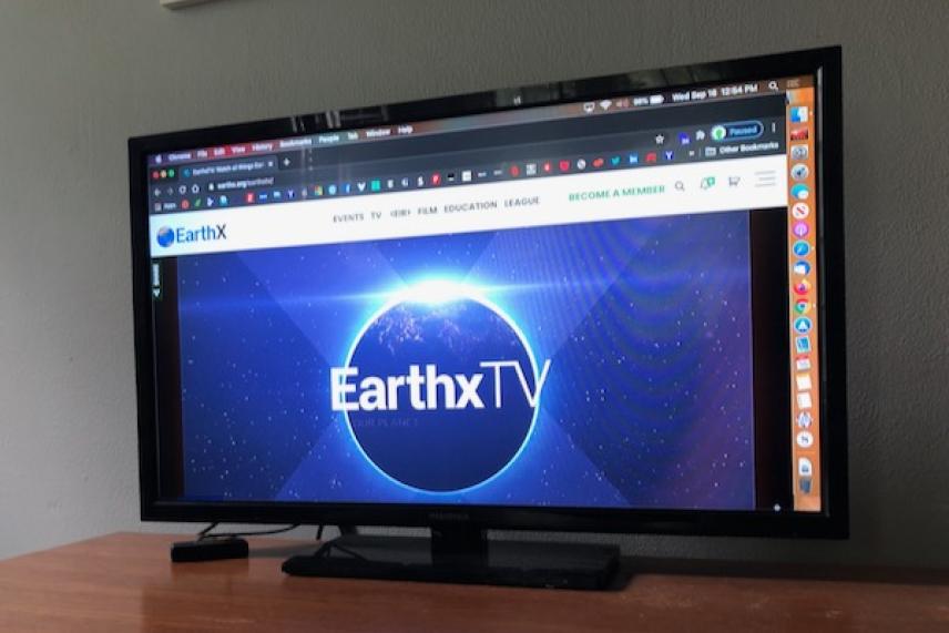 Television displaying EarthxTV website with a glowing Earth logo.