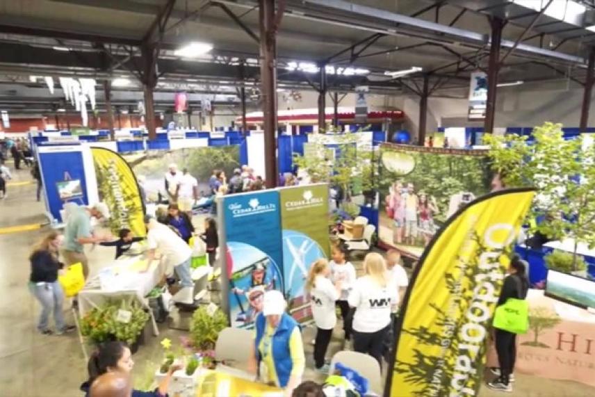 Busy trade show with colorful booths and crowds in a large indoor venue.