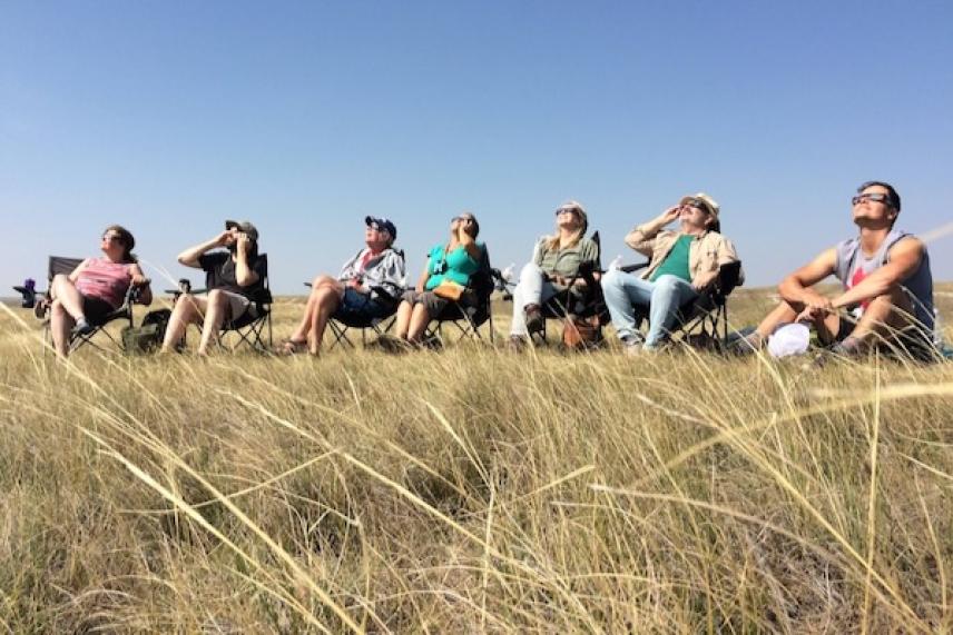 People sitting in a grassy field, looking up at the sky.