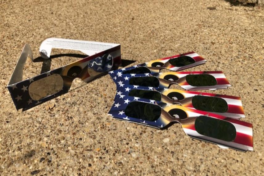 Solar eclipse glasses on a textured surface, with USA flag designs.