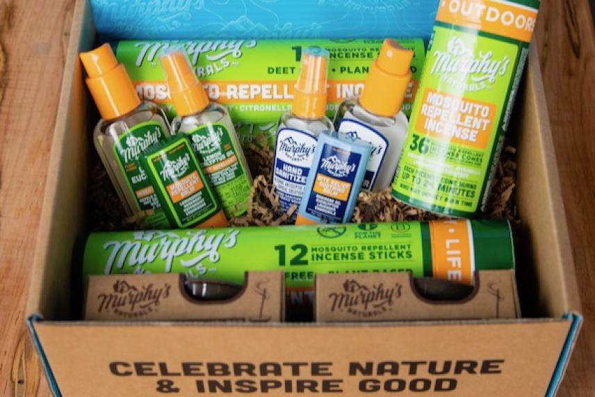 Bug spray and repellent products in a box on a wooden surface.
