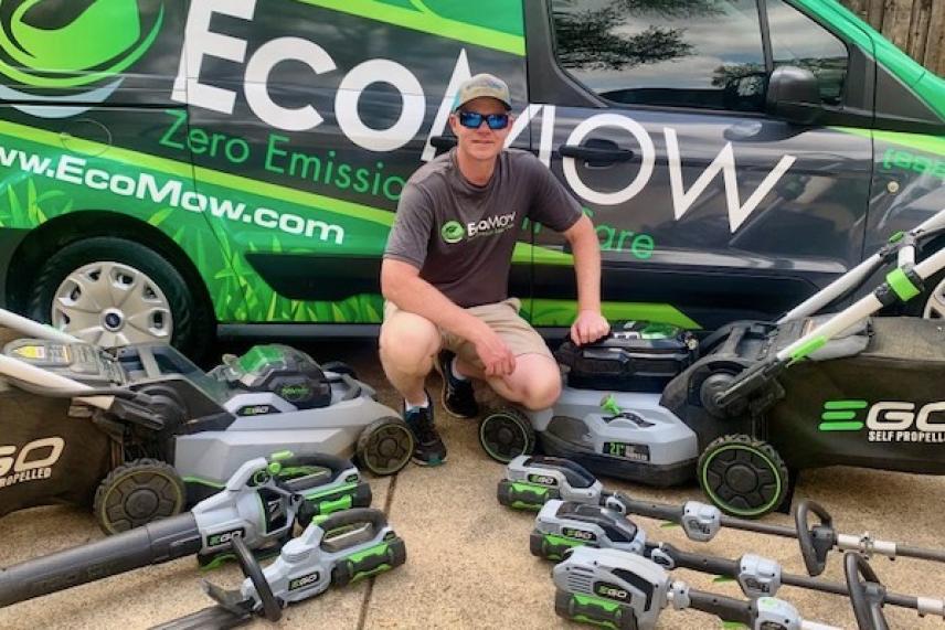 Man kneeling with battery powered tools in front of a van.
