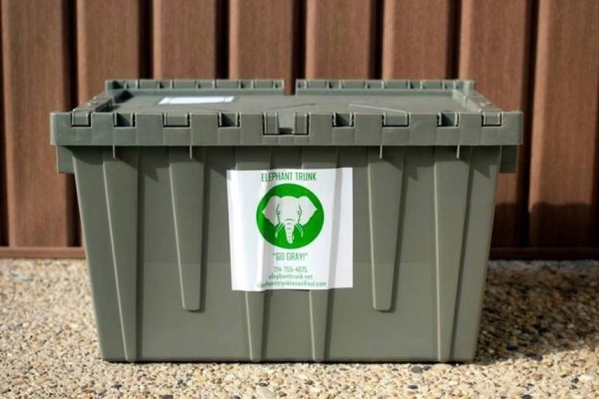 Gray recycling bin with elephant logo in front of a wooden wall.