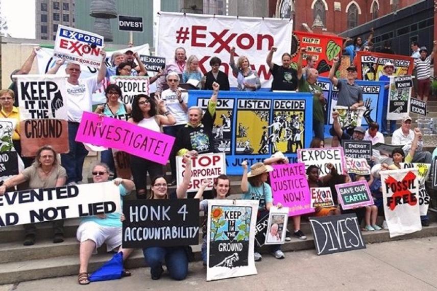 A large group of people holding protest signs outdoors.