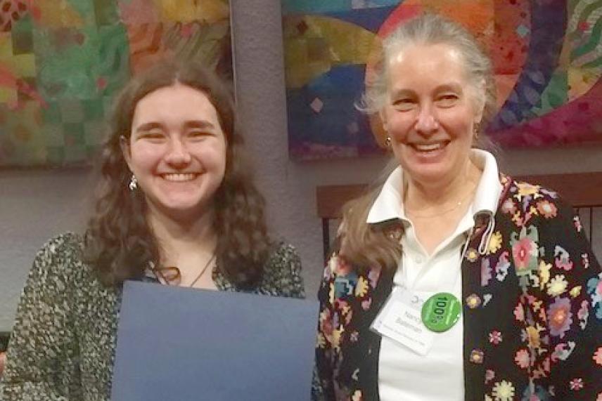 Two women smiling, one holding a certificate, colorful background.