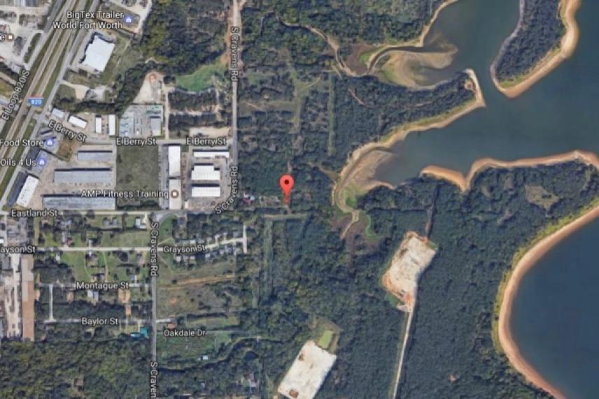 Aerial view of an industrial area beside a forest and lake.
