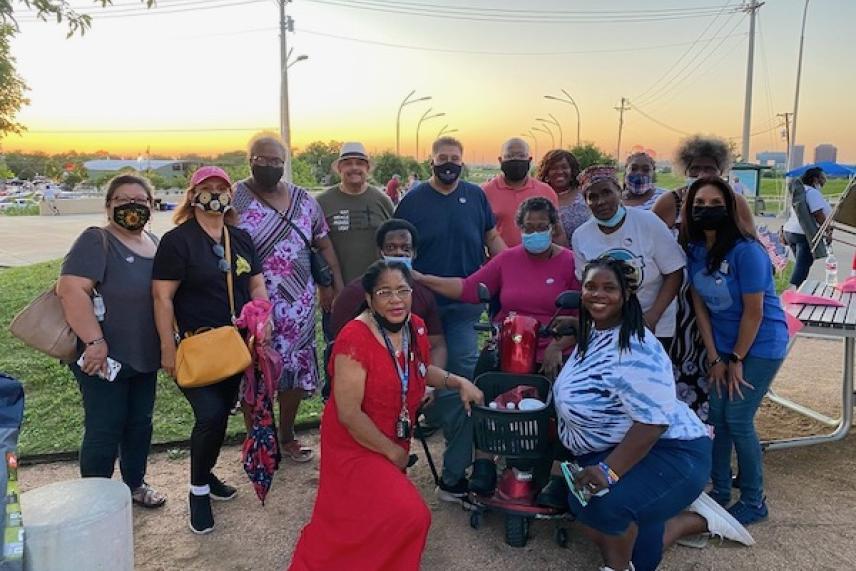 Group of diverse people posing outdoors at sunset, some wearing masks.