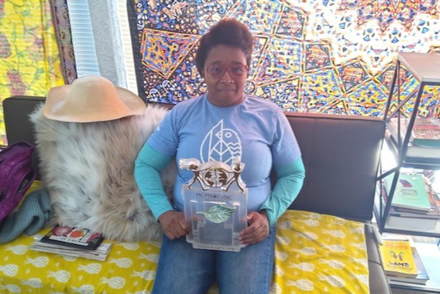 Woman sitting on a sofa holding an ornate box, colorful decor around.