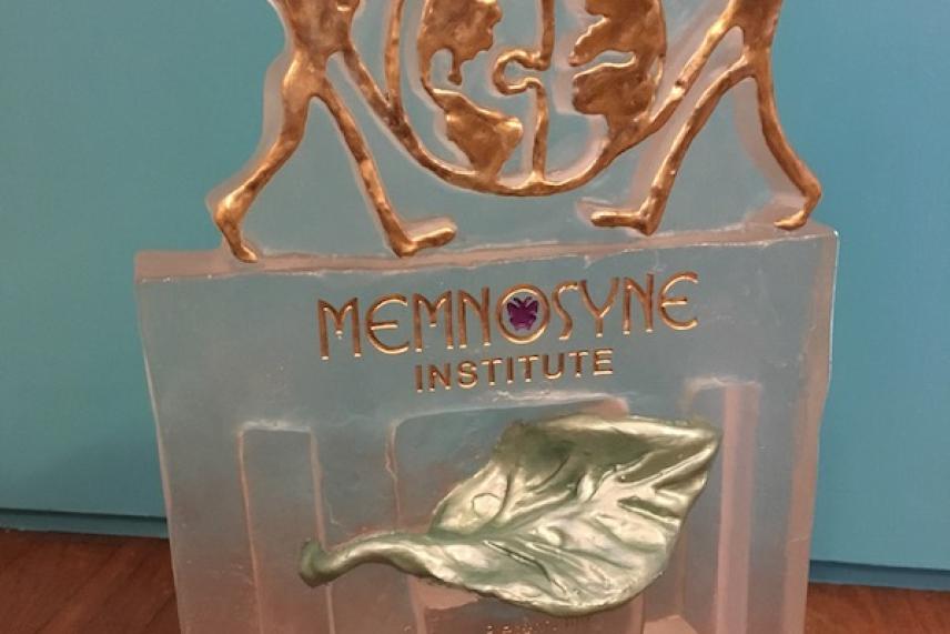 Trophy with bronze figures, green leaf emblem, "Memnosyne Institute" text.