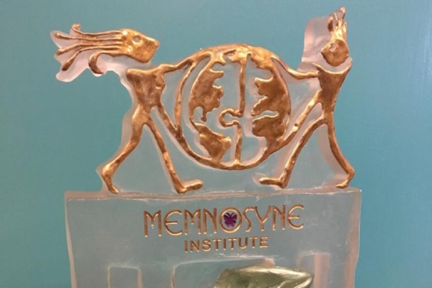 Bronze sculpture of two figures holding a globe on a translucent base.
