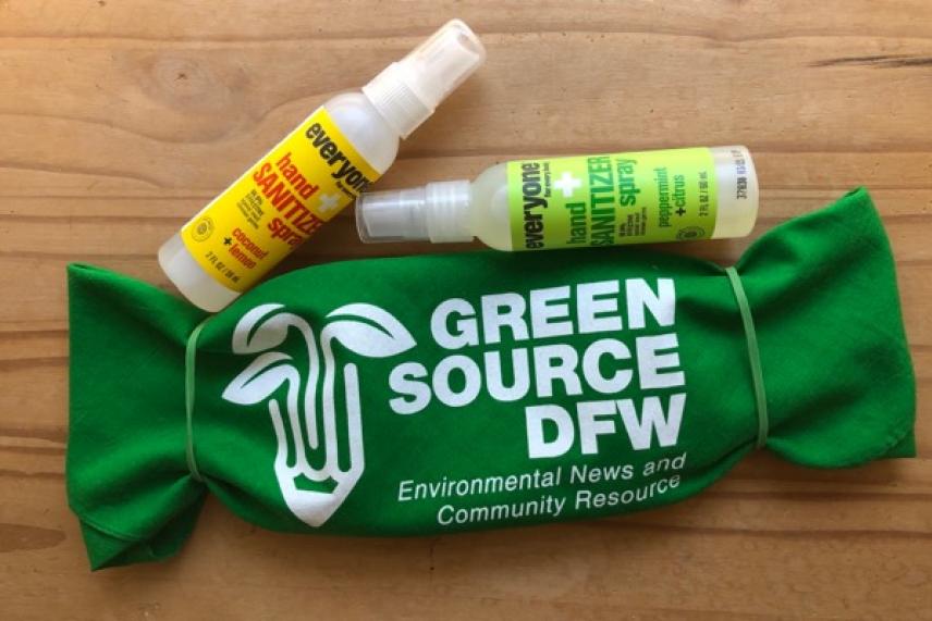 Green pouch with logo, two small spray bottles on wooden surface.