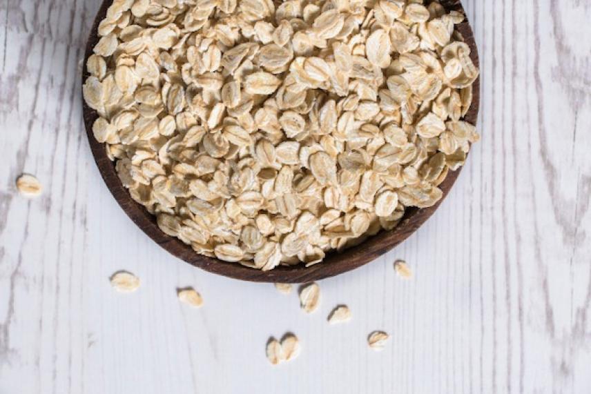 Bowl of rolled oats on a light wooden table.
