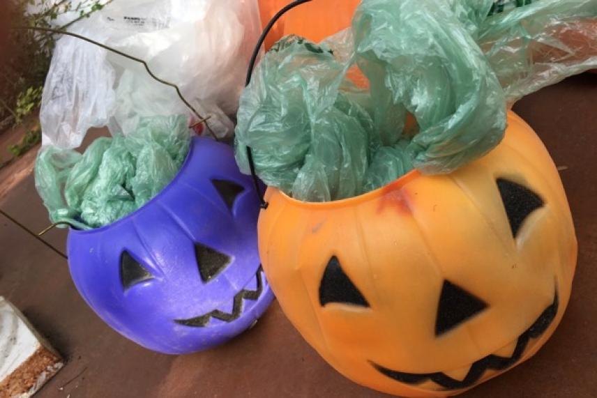 Orange and purple pumpkin buckets filled with green plastic bags.
