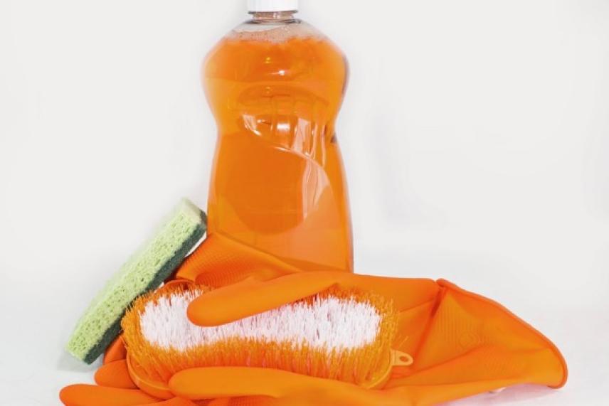 Orange cleaning supplies with gloves, sponge, brush, and detergent.