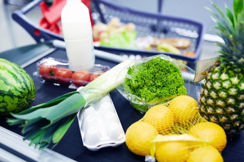 Grocery items on a checkout conveyor, including fruits and vegetables.