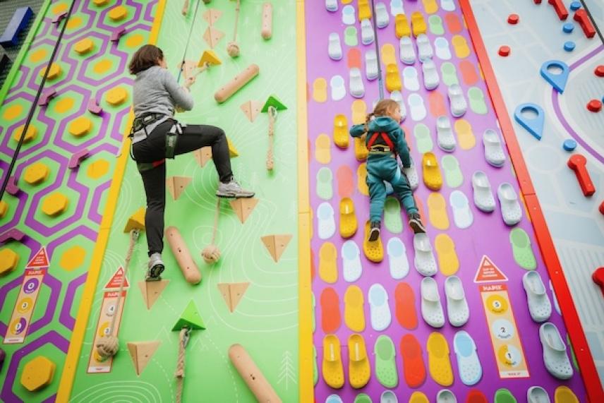 Two people climbing colorful indoor rock walls.